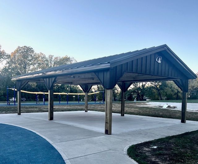 A pavilion in a park with volleyball nets in the background.