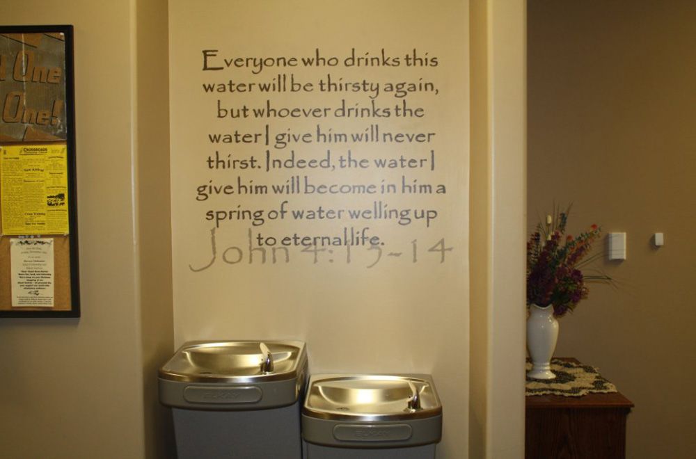A wall with a quote on it that says everyone who drinks this water will be thirsty again